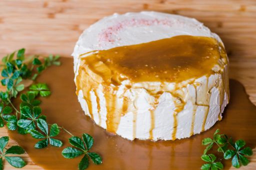 A high angle shot of a freshly baked delicious cake with white creamy frosting and caramel sauce