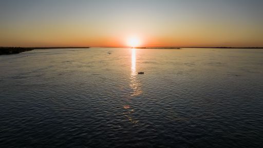 A beautiful sunset over the sea and a boat in the middle of the glowing water surface