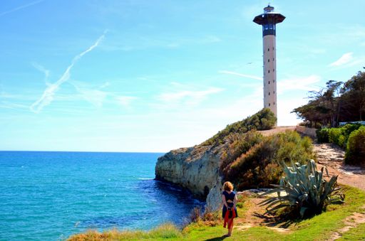 A young female in blue dress walking on the path that leads to Torredembarra lighthouse