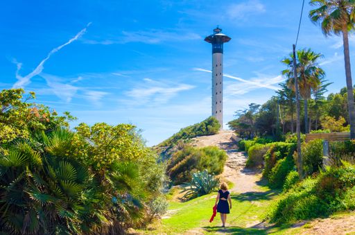 A young female in blue dress walking on the path that leads to Torredembarra lighthouse