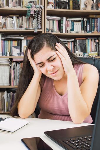 A young entrepreneur woman suffering from a headache while working from home