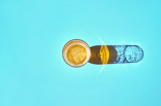 A top view of a glass of beer with the shadow reflected on the blue table