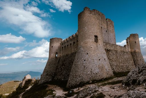 The Rocca Calascio on a hill under a blue cloudy sky in Abruzzo, Italy