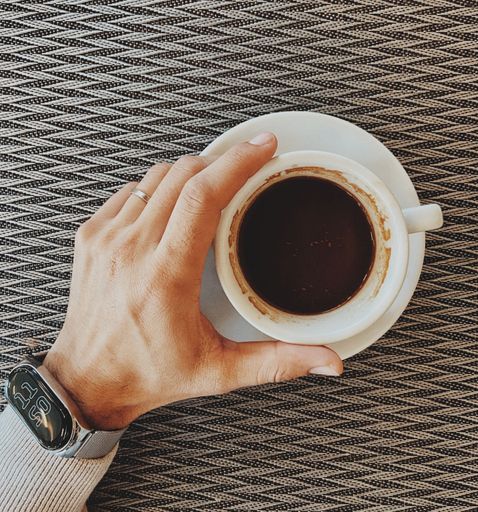 A top-view shot of a man's hand holding a cup of coffee