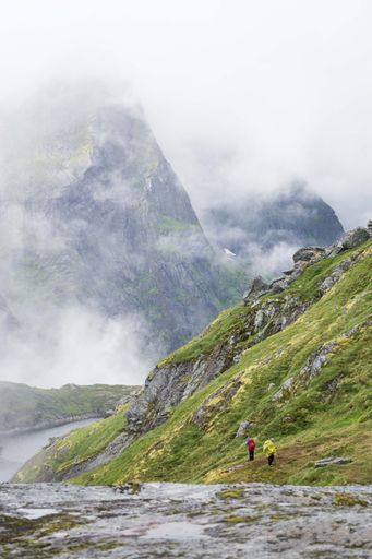 A vertical shot of people hiking in the mountains of Lofoten Islands on a foggy weather