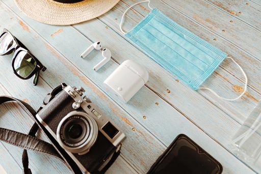 An overhead shot of must-needed tools for every traveler placed on a wooden table
