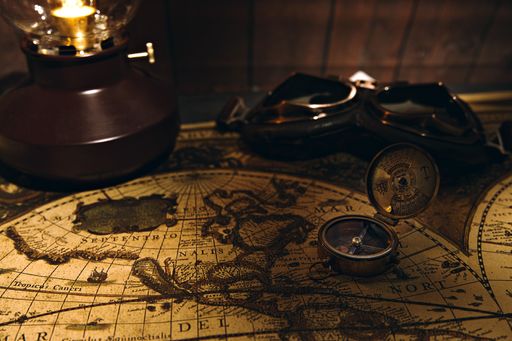 A vertical shot of a vintage compass and map on a wooden surface, vintage adventure kit starter pack