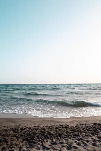 A beautiful view of sea waves splashing on a beach on a sunny day