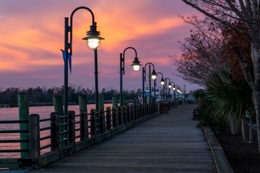 An empty boardwalk illuminated by lanterns during beautiful sunset in Wilmington, North Carolina