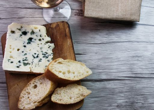 A high angle shot of a piece of delicious Roquefort cheese with bread slices and a glass of wine on the table