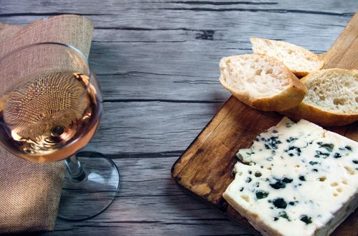 A high angle shot of a piece of delicious Roquefort cheese with bread slices and a glass of wine on the table