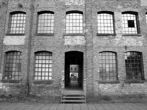 A grayscale shot of an old brick wall building with glass windows