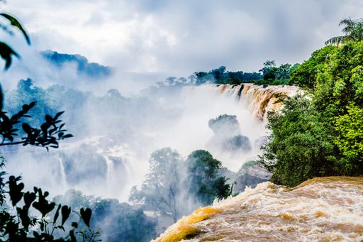 The waterfall at Iguazu National Park surrounded by forests covered in fog under a cloudy sky