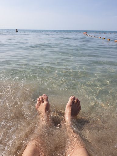 A vertical shot of a person's feet on the beach