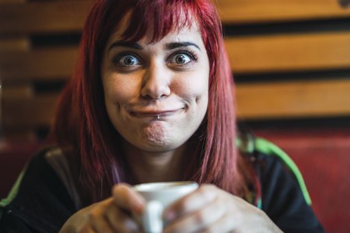 A Caucasian woman with red hair and piercing drinking tea