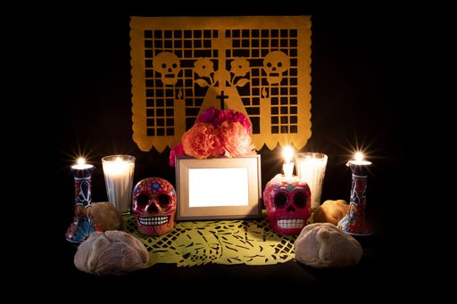 Mini altar for the day of the dead in Mexico with candles, colored skulls, and flowers