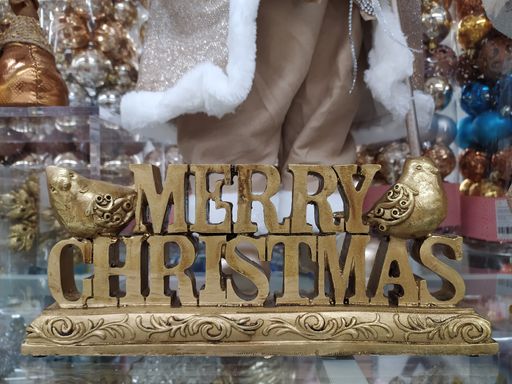 A closeup of an ornamental wooden engraved "Merry Christmas" and birds