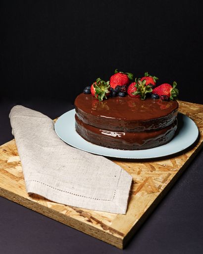 A vertical shot of a delicious chocolate cake decorated with strawberries and blueberries