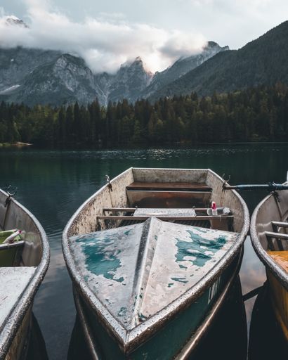 A line of old wooden boats in Fusine lake with green mountains around, Italy