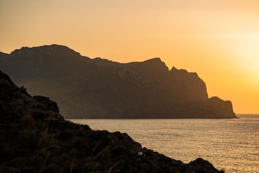 A scenic sunset view with coastal rugged against the orange sky