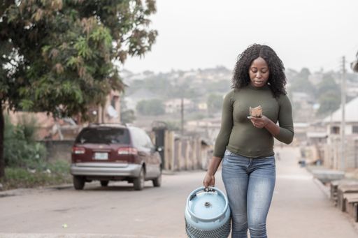 unhappy nigerian lady going to fill her gas cylinder