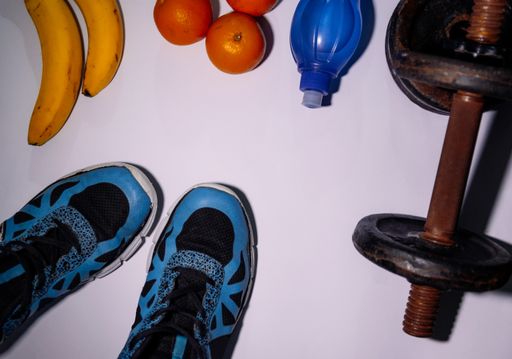 A flat lay shot of sports activity set with fresh healthy fruits on a white surface with a copy space