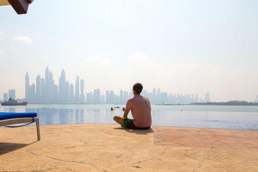 A young man sitting at pool from behind
