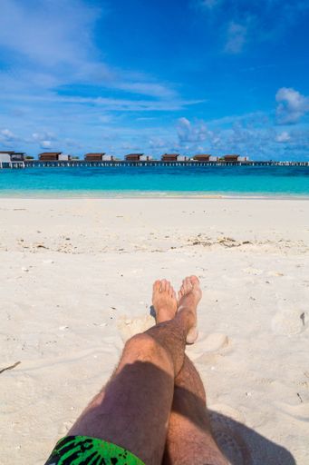 A vertical shot of male legs on background of a beach in the Maldives