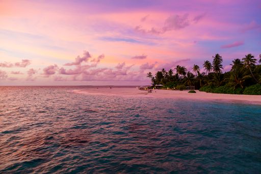 A breathtaking view of the wavy ocean gleaming under the cloudy purple sky - great for wallpapers