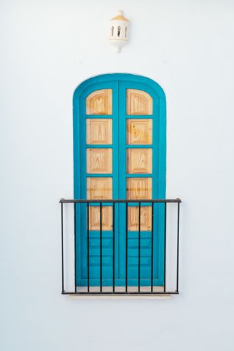 A blue balcony door boarded with wood on a white wall