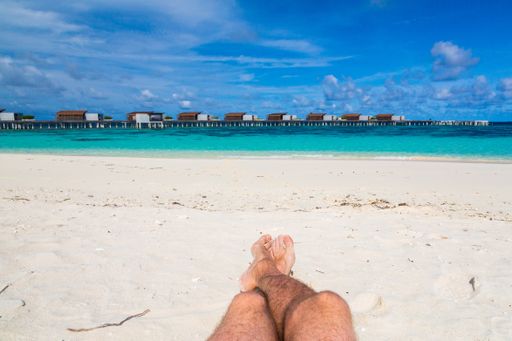 A closeup of male legs on background of a beach in the Maldives