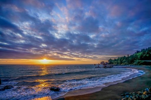 A breathtaking shot of the sun rising over the ocean under the cloudy sky