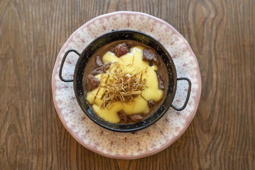 A top view of a beef dish with melted cheese on top