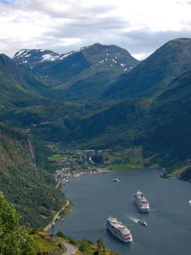 A vertical aerial shot of ships in the sea near mountains in Norway