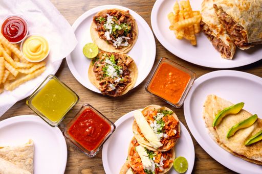 A top view of french fries and delicious meat and vegetable wraps on plates on the table