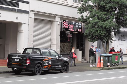 View of city scene with black pickup car driving paying for parking and people walking along the street