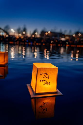 A selective focus vertical image of lanterns floating on water at dark during festival in Austin, Texas