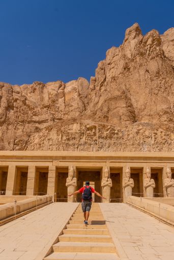 A vertical shot of a Caucasian male travelling in the Mortuary Temple of Hatshepsut, Egypt