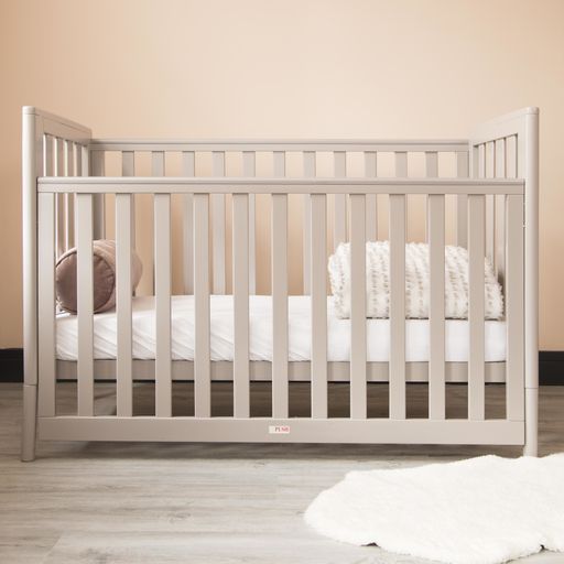 A modern baby room interior with a cozy classic crib and a soft neckroll pillow with blanket