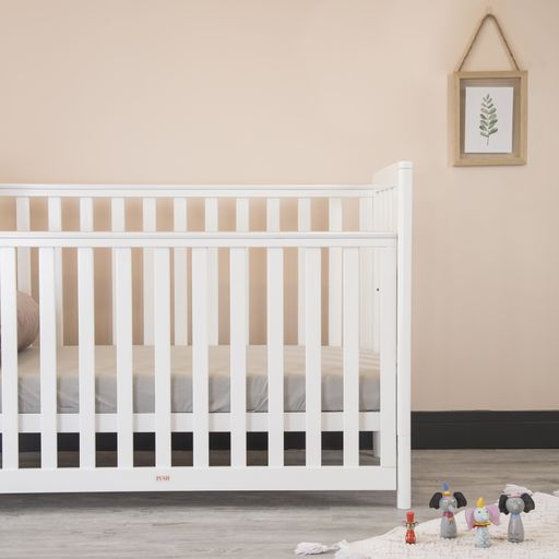 A modern baby room interior with a cozy classic crib and miniature toys placed on a soft carpet