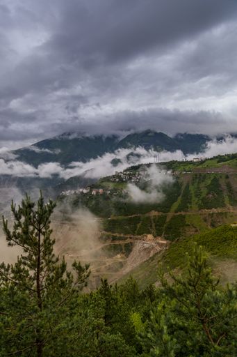 A vertical shot of the grass covered fields and mountains under the beautiful cloudy sky