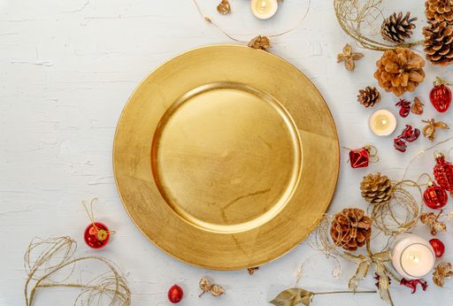 An overhead shot of a golden plate with rustic colorful Christmas decors on white wooden table