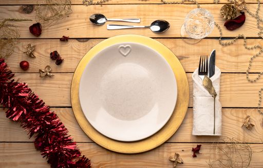 A top view of cutlery and plates on festive wooden background