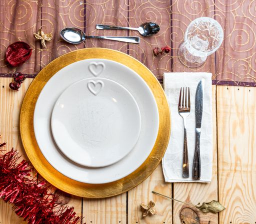 A top view of cutlery and plates on festive wooden background