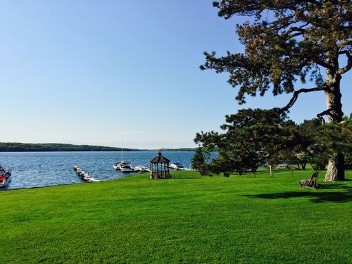 The shoreline of Skaneateles lake with anchored boats, surrounded by green vegetation, New York