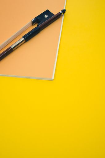 A closeup of a violin bow on a paper on the yellow surface - space for text