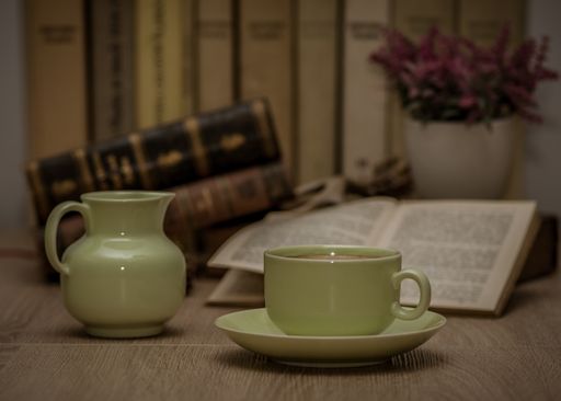 A closeup shot of a cup of tea jug and a book