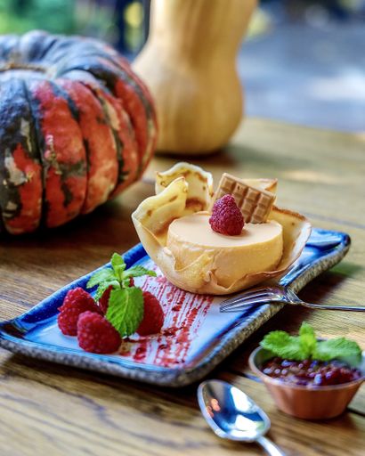 A vertical shot of ice cream in a waffle with raspberries on a tray in a cafe