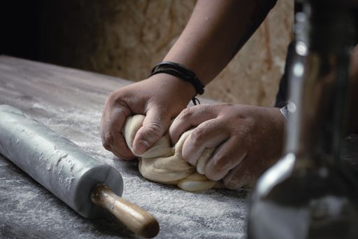 A closeup shot of a baker mixing the dough with flour
