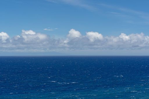 The blue sea waves under a blue sky with clouds.